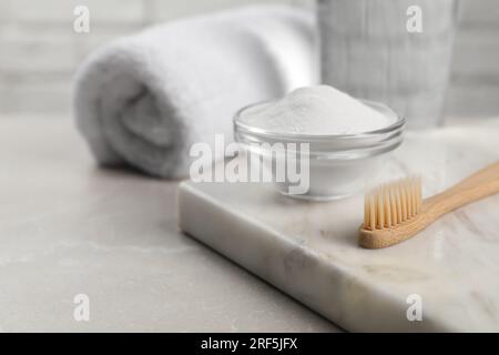Bambuszahnbürste und Glasschüssel mit Backpulver auf einem hellen Tisch, Platz für Text Stockfoto