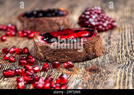 Törtchen mit Beerenfüllung auf dem Küchentisch, köstliches Dessert aus Teig mit Beeren und Buttercreme Stockfoto