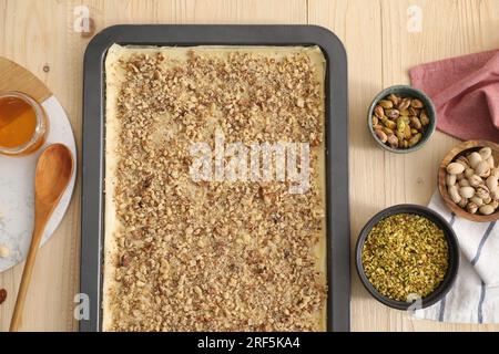 Ich mache köstliche Baklava. Backpfanne mit Teig und Zutaten auf Holztisch, flach liegend Stockfoto