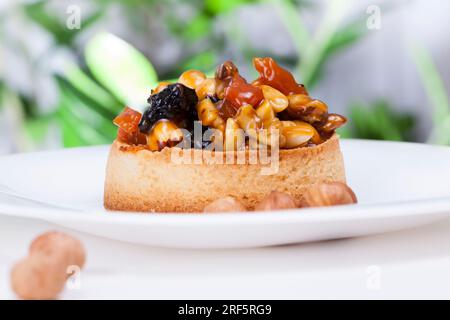 Kleine runde Törtchen mit verschiedenen Füllungen, knusprige Törtchen mit Haselnüssen, Erdnüssen und anderen Zutaten, Teig Törtelnüsse und getrocknete Obstbucht Stockfoto