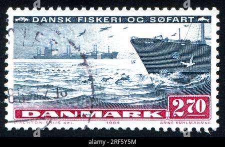 DÄNEMARK - CIRCA 1984: Stempel gedruckt von Dänemark, zeigt Delfin und Schiff, circa 1984 Stockfoto