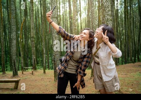 Zwei asiatische Frauen wandern zusammen und machen Selbstporträts im Wald. Reiseaktivität Stockfoto