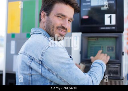 Emotionaler Geschäftsmann, der sich beim Benzin bedient Stockfoto