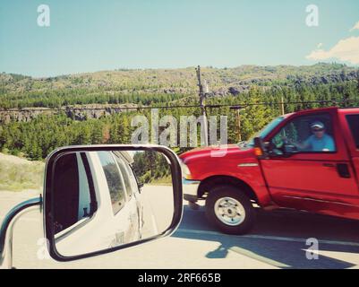 Blick von der Seite oder vom seltenen Spiegel eines Kleinwagens auf eine Autobahnstraße in Okanagan Falls, British Columbia, Kanada. Stockfoto