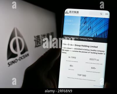 Person, die ein Smartphone mit einer Webseite des Unternehmens Sino-Ocean Group Holding Limited auf dem Bildschirm vor dem Logo hält. Konzentrieren Sie sich auf die Mitte des Telefondisplays. Stockfoto