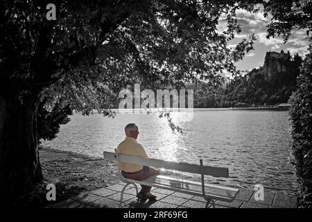 Der leere Platz auf der Bank - ein älterer Mann, der allein am Bleder See sitzt Stockfoto