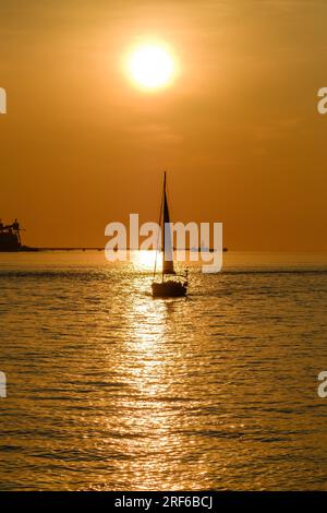 Ein Segelboot auf dem Fluss Tage in Lissabon, Portugal, während die Sonne untergeht Stockfoto