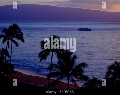 Blick in den Park des Hotel Royal Lahaina Resort im Westen der Insel und über Kaanapali Beach zur benachbarten Insel in der Abenddämmerung. USA- Stockfoto