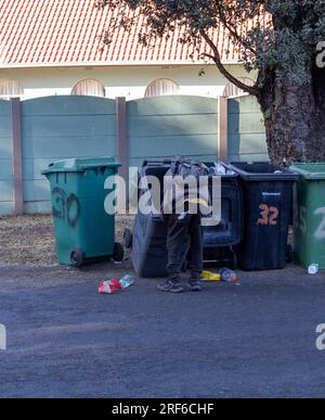 Johannesburg, Südafrika - ein unbekannter Schwarzer gräbt in Mülltonnen nach recyclingfähigem Material Stockfoto