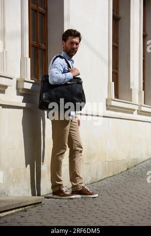 Hübscher Geschäftsmann auf der Straße, mit luxuriöser schwarzer Lederaktentasche. Modischer Style. Stockfoto