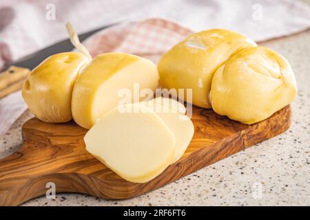 Geräucherter Scamorza-Käse auf dem Schneidebrett. Stockfoto