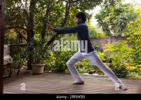 Fokussierter indianer, der Yoga auf der sonnigen Terrasse praktiziert, Kopierraum Stockfoto