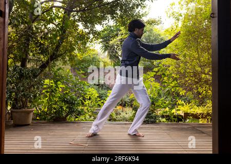 Fokussierter indianer, der Yoga auf der sonnigen Terrasse praktiziert, Kopierraum Stockfoto