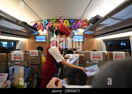 (230801) -- TIANJIN, 1. August 2023 (Xinhua) -- Ein Dirigent überreicht einem Passagier an Bord eines Zuges, der auf der Intercity-Eisenbahn Peking-Tianjin verkehrt, am 1. August 2023 ein 15.-jähriges Andenken. Die Peking-Tianjin Intercity Railway feierte ihren 15. Jahrestag der Eröffnung am Dienstag. Als erste Hochgeschwindigkeitsbahn (HSR) mit einer theoretischen Geschwindigkeit von 350 km/h in China hat sie seit ihrer Inbetriebnahme insgesamt 340 Millionen Fahrgäste befördert.bis 2022 hatte China 42.000 km betriebsbereite HSR und rangierte damit weltweit an erster Stelle. Und die Länge der Hochgeschwindigkeitsbahn, die regelmäßig mit 350 km/h in der Nähe verkehrt Stockfoto