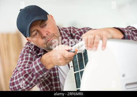 Männlicher Techniker, der das tragbare Heizelement repariert Stockfoto