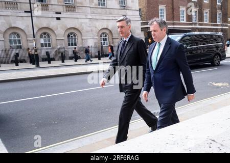 Die konservativen Abgeordneten Jacob Rees-Mogg (links) und Edward Argar gehen am Treasury Building in Whitehall in London vorbei, 25. Juli 2023. Foto: Rob Watkins Stockfoto