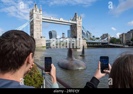 London, Großbritannien. 1. August 2023. Die Menschen sehen zwei der drei riesigen Megalodon-Haifischflossen, die sich scheinbar an der Oberfläche der Themse in der Nähe der Tower Bridge erheben, um die Freisetzung der Warner Bros. In Großbritannien am 4. August zu fördern Filmfilm „Meg 2: The Trench“ mit Jason Statham. Laut dem Naturkundemuseum war die prähistorische Art, bekannt als Otodus megalodon, der größte Hai der Welt und einer der größten Fische, die es je gab. Kredit: Stephen Chung / Alamy Live News Stockfoto