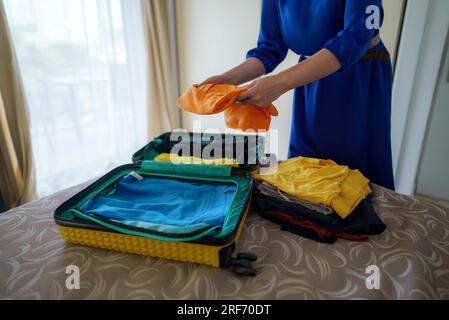 Die Frau packt Kleider in den Koffer. Ich bereite mich auf die Reise vor. Stockfoto