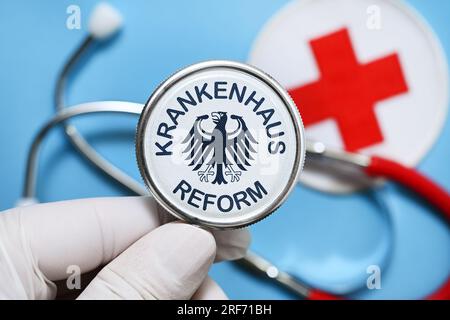 FOTOMONTAGE, Hand hält Stethoskop mit Aufschrift Krankenhausreform und Bundesadler Stockfoto