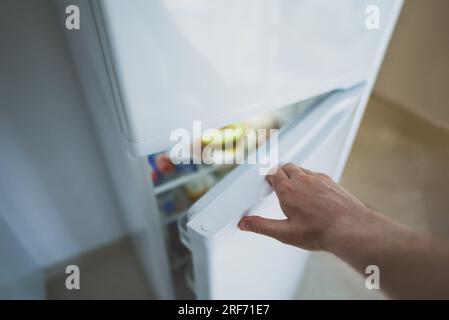 Mann öffnet Tür des Kühlschranks mit Essen. Stockfoto