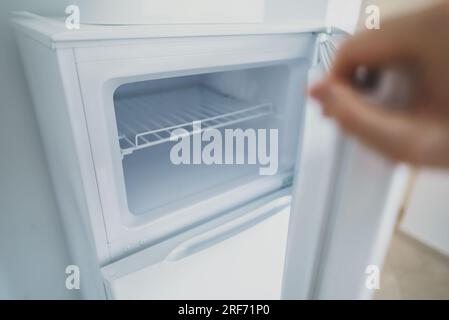 Ein Mann sieht sich einen leeren offenen Gefrierschrank im Kühlschrank an. Stockfoto