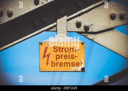 FOTOMONTAGE, Hochspannungsmast mit Schild und der Aufschrift Strompreisbremse Stockfoto