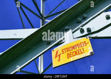 FOTOMONTAGE, Hochspannungsmast mit Schild und der Aufschrift Strompreisdeckel Stockfoto