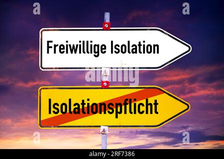 FOTOMONTAGE, Wegweiser mit Aufschrift Freiwillige Isolation und Isolationspflicht Stockfoto