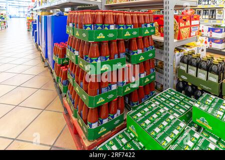 Italien - 29. Juli 2023: Tomatenpüree in Glasflaschen in Kartons auf einer Palette im Gang eines italienischen Discount Stores DER PAN Group Stockfoto