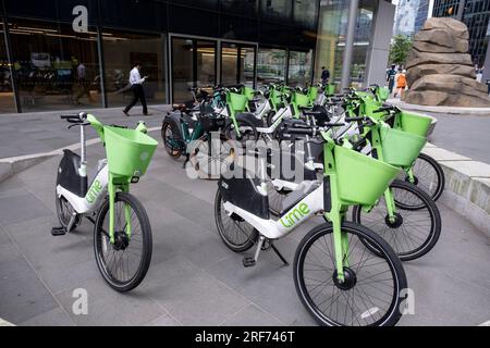 Am 6. Juli 2023 in London, Vereinigtes Königreich, auf der anderen Straßenseite geparkte Limettenelektrofahrräder. Ein Fahrrad-Sharing-System oder ein Fahrrad-Sharing-Programm ist ein gemeinsamer Transportservice, bei dem Fahrräder für die gemeinsame Nutzung durch Einzelpersonen gegen eine Gebühr zur Verfügung stehen. Die Programme selbst umfassen sowohl Docking- als auch docklose Systeme. Stockfoto