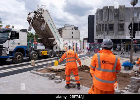 Ein Team von Arbeitern, die orangefarbene Overalls auf einer Baustelle tragen, arbeiten an der Fertigstellung der neuen Bahn für die Modernisierung des öffentlichen Nahverkehrssystems Midland Metro im Stadtzentrum entlang der Bull Street, gleich neben der Corporation Street am 20. Juli 2023 in Birmingham, Vereinigtes Königreich. Die neue Linie soll im Laufe des Jahres eröffnet werden. Die Midland Metro ist eine Straßenbahnlinie in der Grafschaft West Midlands, England, die zwischen den Städten Birmingham und Wolverhampton über die Städte West Bromwich und Wednesday verkehrt. Die Linie wird auf Straßen in städtischen Gebieten eingesetzt und wieder aufgefüllt Stockfoto