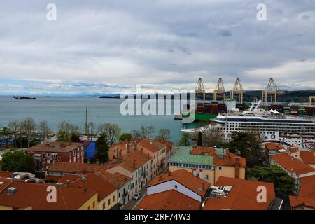 Koper, Slowenien - April 16 2023: Blick auf die Stadt Koper und den Hafen von Koper mit einem angedockten Kreuzfahrtschiff und alpengipfeln in der Ferne Stockfoto