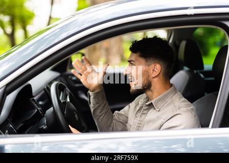 Junger Mann, der Auto fährt, mit wütendem Gesichtsausdruck auf der Straße Stockfoto