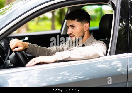 Profilansicht eines gutaussehenden jungen Mannes, der sein Auto auf der Straße fährt Stockfoto