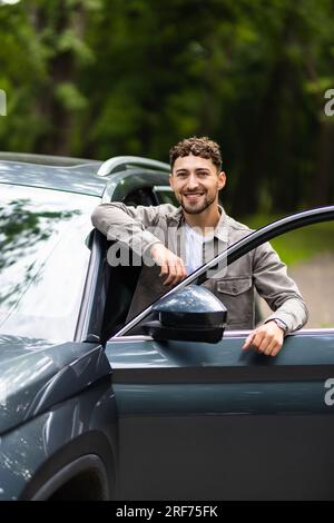 Lächelnder Mann stand neben seinem Auto Stockfoto