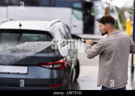 Mann sein Auto waschen unter hohem Druck Wasser im Freien Stockfoto