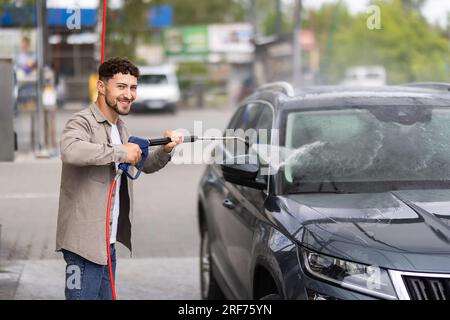 Mann sein Auto waschen unter hohem Druck Wasser im Freien Stockfoto