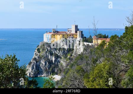 Blick auf Castello di Duino auf einer Klippe über der Adria in der italienischen Region Friaul-Julisch Venetien mit immergrüner mediterraner Vegetation Stockfoto