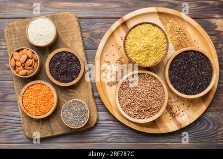 Verschiedene Superfoods in der kleinen Schüssel auf farbigem Hintergrund. Superfood wie Reis, Chia, Quinoa, Linsen, Nüsse, Sesamsamen, Mandeln. Draufsicht. Stockfoto