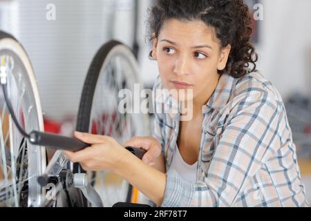 Frau pumpt einen Fahrradreifen mit einer kleinen Handpumpe auf Stockfoto