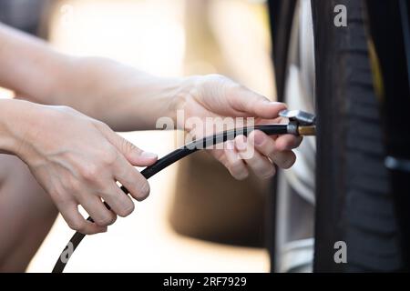 Person, die den Reifendruck von Pkw mit einem Manometer misst Stockfoto