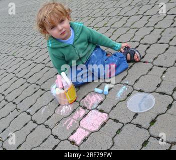 kleiner Junge spielt mit Strassenmalkreide | kleiner Junge spielt mit Buntstift Stockfoto