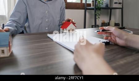 Immobilienmakler sprach über die Bedingungen des Hauskaufvertrags und bat den Kunden, die Dokumente zu unterzeichnen, um den Vertrag legal zu machen Stockfoto