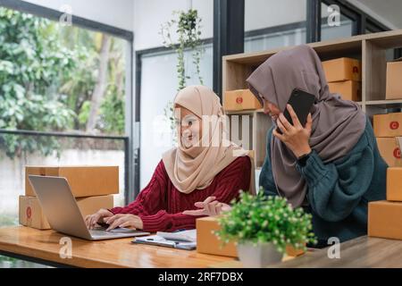 Moslem zwei Freiberuflerinnen kmu-Unternehmen Online-Shopping mit Laptop-Computer und Checklisten-Bestellbox zu Hause Business Online-Versand und Stockfoto
