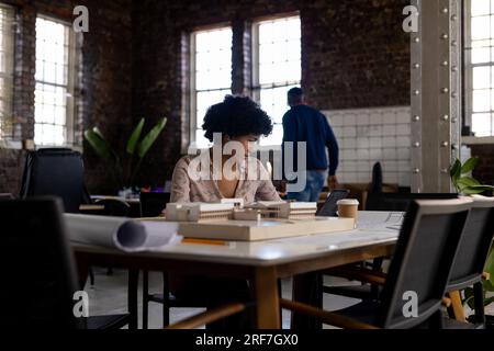 Birassische Architektin, die am Schreibtisch sitzt und sich ein Modell im Büro ansieht Stockfoto