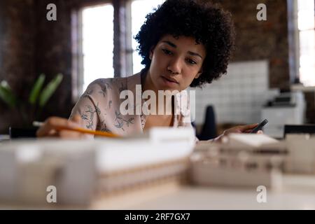 Birassische Architektin, die am Schreibtisch sitzt und sich ein Modell im Büro ansieht Stockfoto