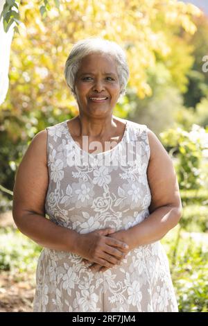 Porträt einer glücklichen älteren, birassischen Frau, die zu Hause im sonnigen Garten lächelt Stockfoto