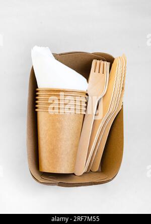 Umweltfreundliche Einwegverpackungen für Lebensmittel. Braune Papierbehälter, Getränkegläser, Gabeln und Messer. Modell, Vorlage. Stockfoto