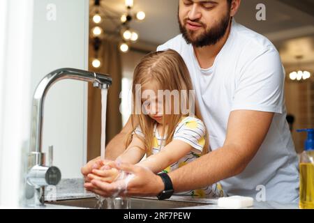 Vater und Tochter waschen sich die Hände über dem Waschbecken in einer Küche Stockfoto