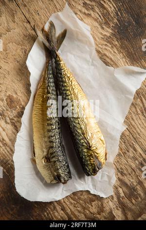 Zwei heiße geräucherte Makrelen, Scomber scombrus auf einem Holzbrett, das zur Herstellung einer hausgemachten Makrelenpastete verwendet wird. England GB Stockfoto